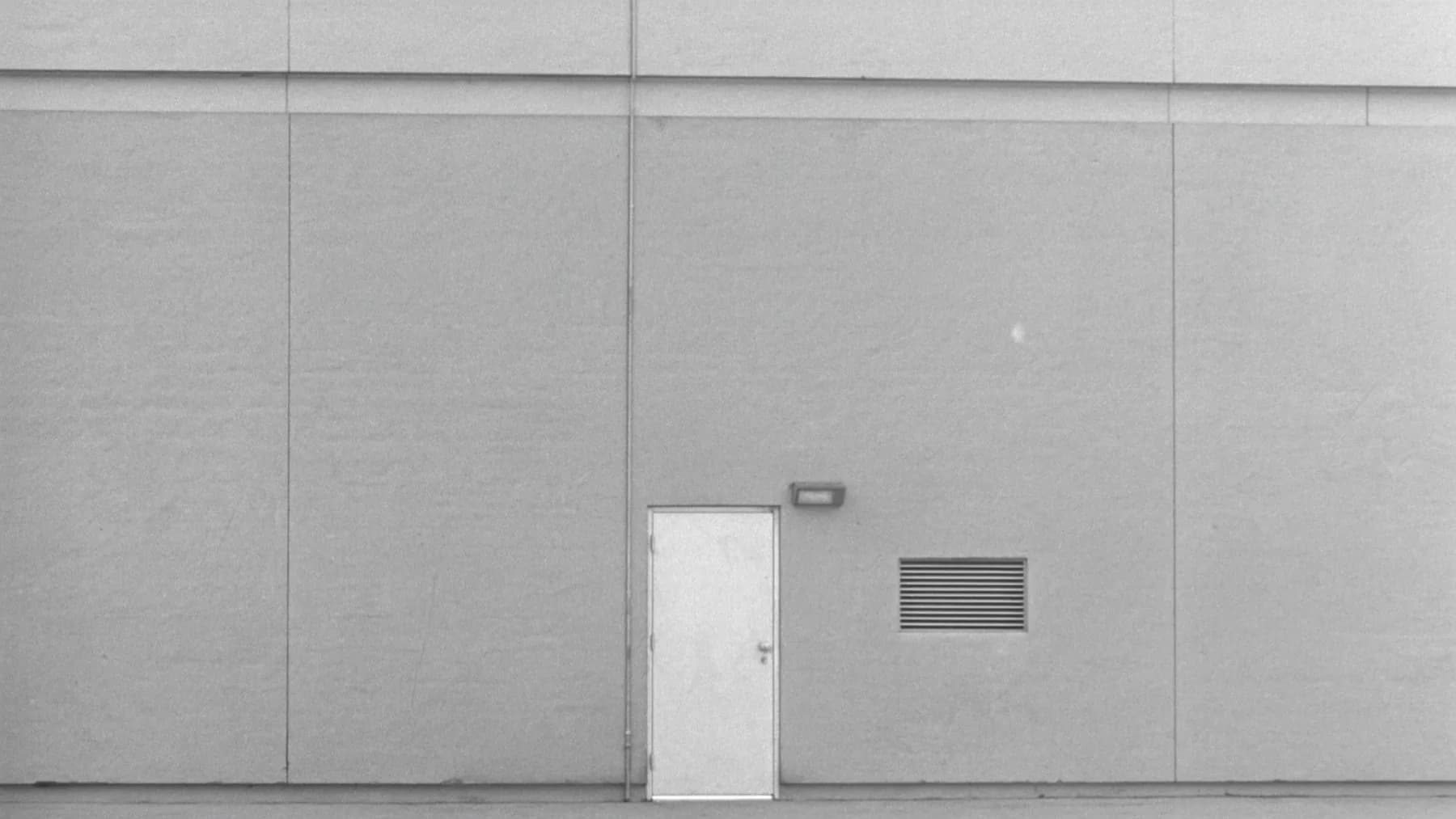 The plain service door at the rear of an office building, photographed square-on
